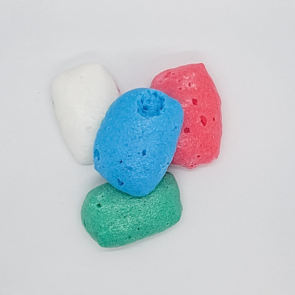 Multicolored freeze dried candy pieces blue white green and red on a white background