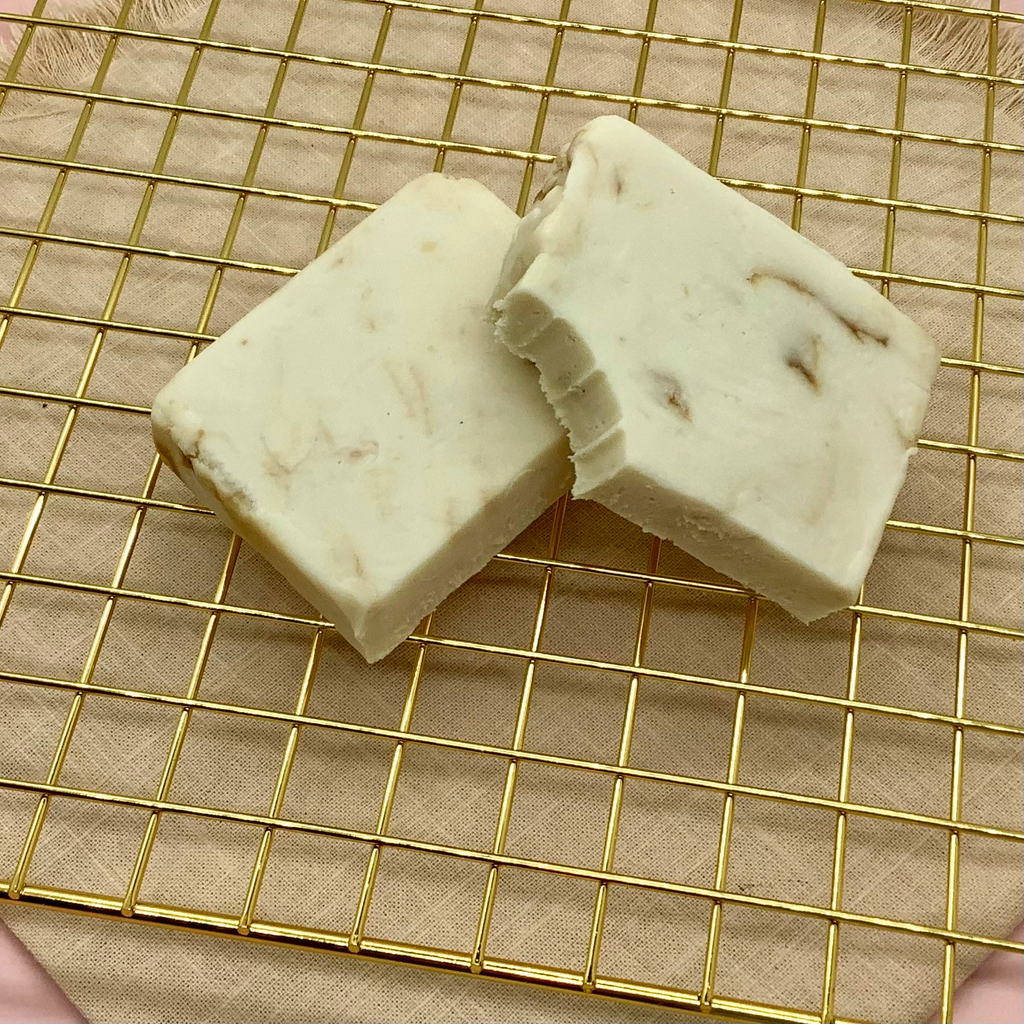 Two white Biscoff cheesecake fudge bars on a gold cooling rack