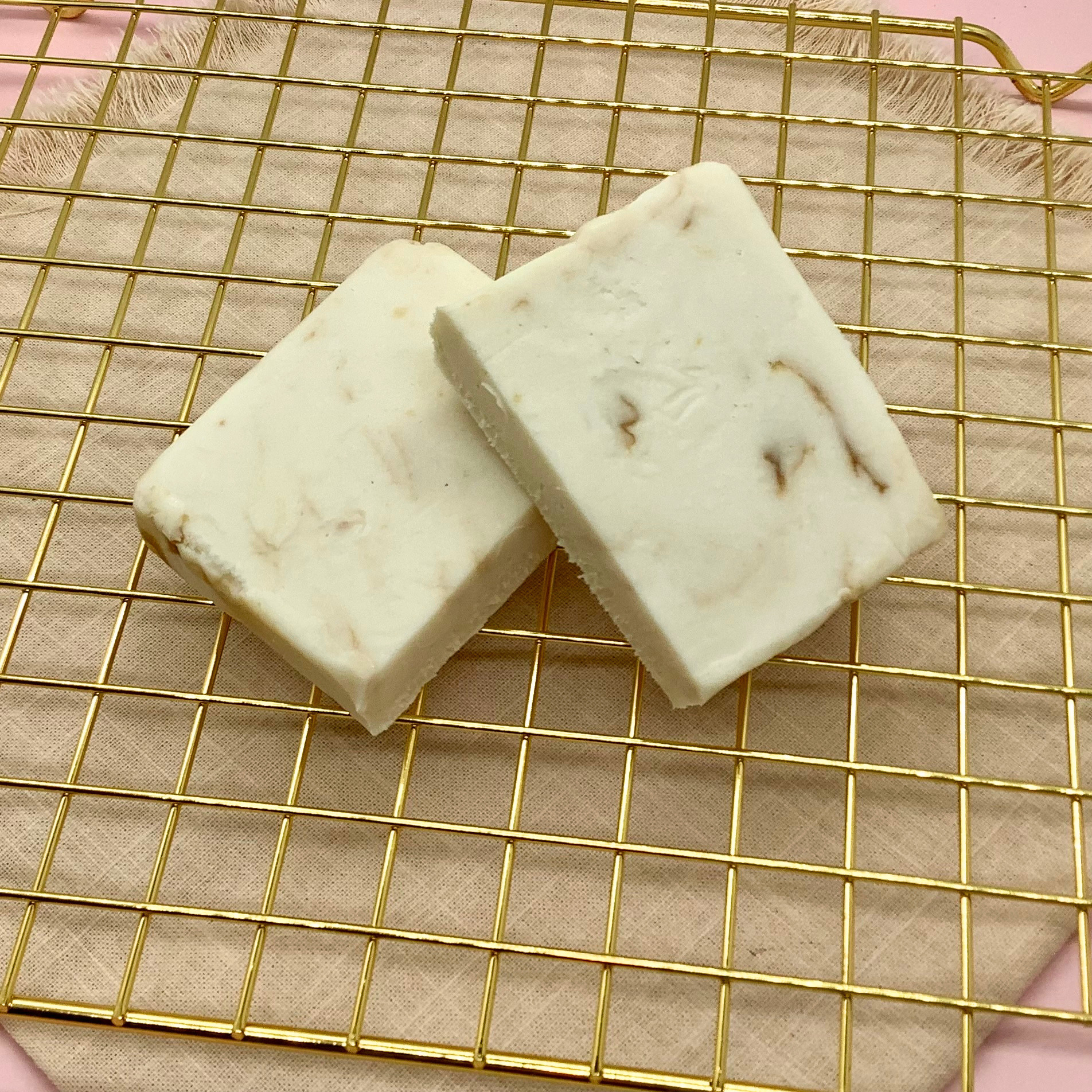 White Biscoff cheesecake fudge blocks with brown swirls on a gold cooling rack