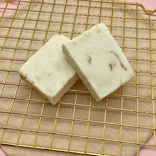 White Biscoff cheesecake fudge blocks with brown swirls on a gold cooling rack