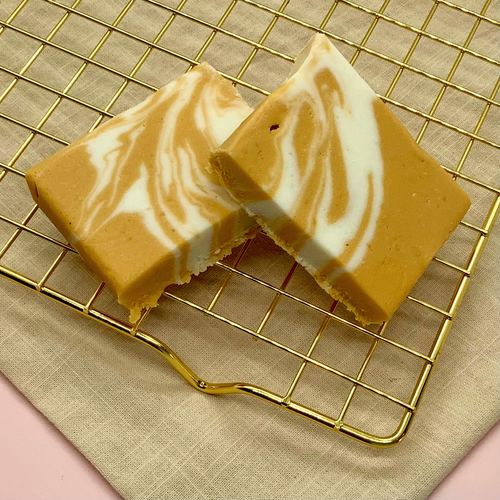 Butter Beer Fudge bars with caramel and vanilla swirls on a pink background