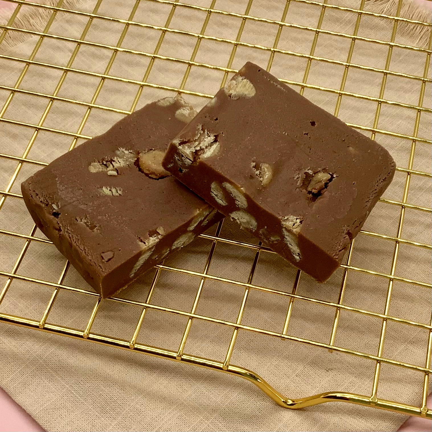 Chocolate peanut butter fudge slabs studded with peanuts on a gold cooling rack