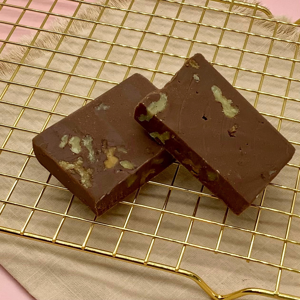 Chocolate walnut fudge blocks with walnut chunks on a gold cooling rack