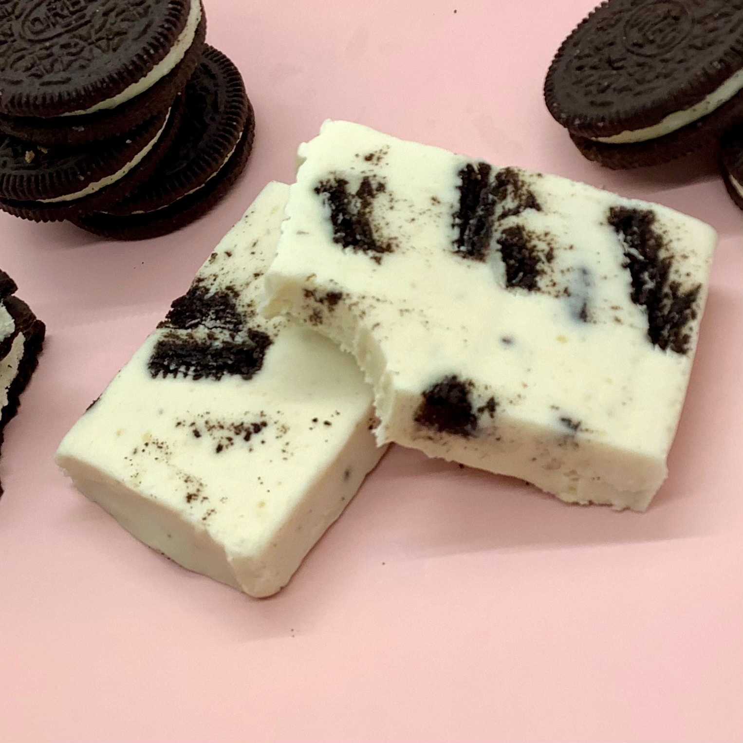 Cookies n' Cream Fudge bar with Oreo pieces on a pink background