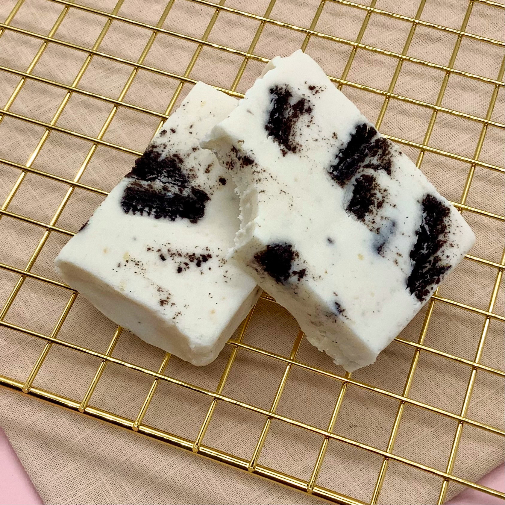 Cookies n' Cream Fudge squares with cookie pieces on a gold cooling rack
