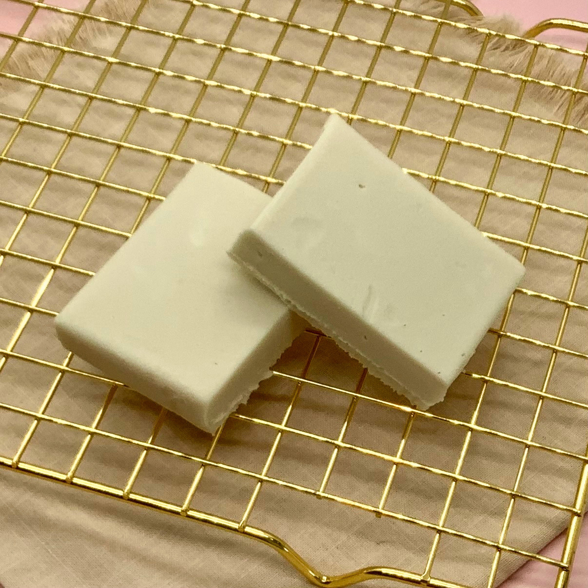 Two white maple fudge blocks on a gold cooling rack