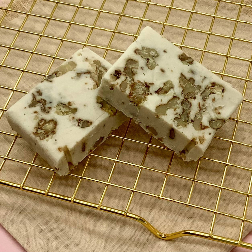 Maple Walnut Fudge squares studded with walnut pieces on a gold cooling rack