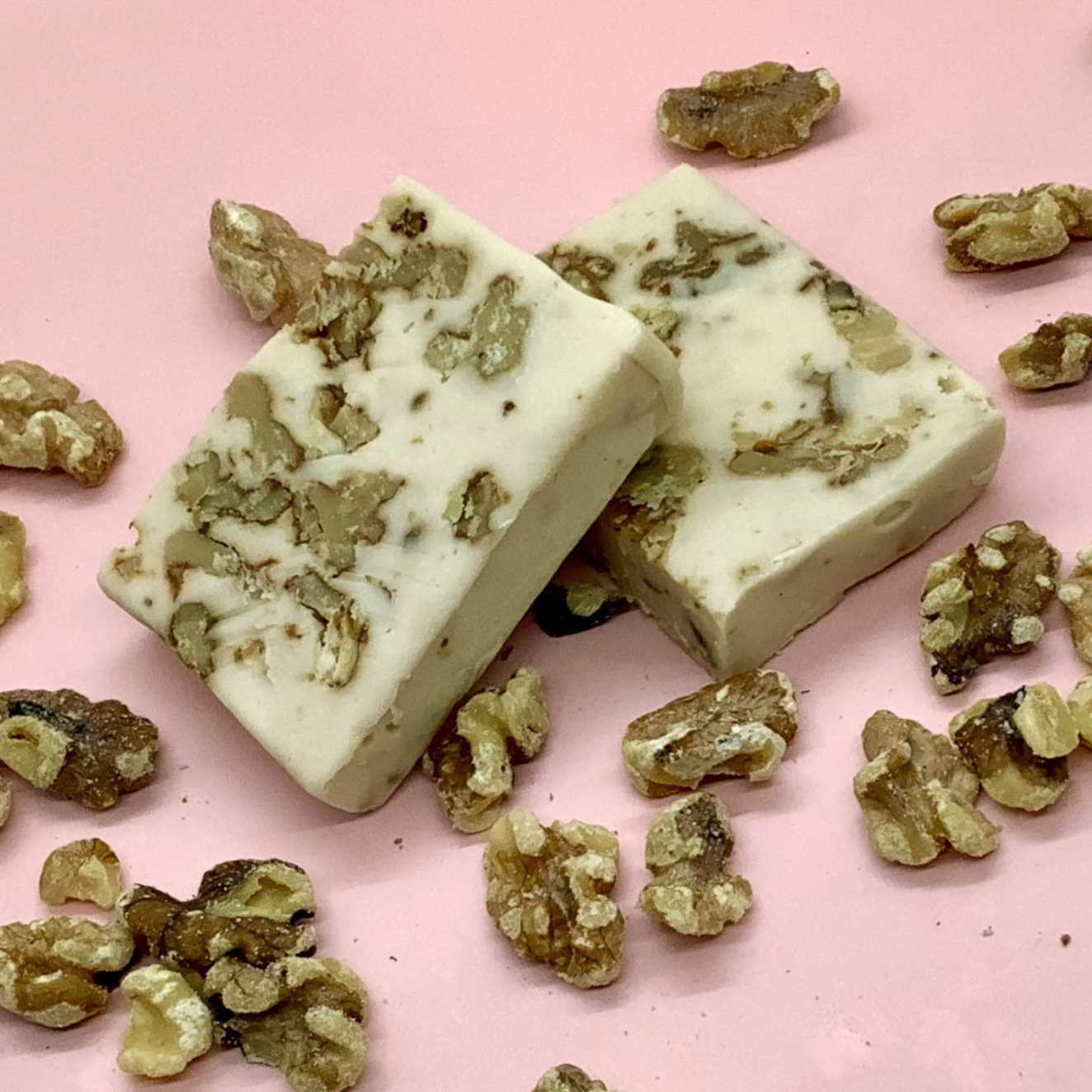 Maple Walnut Fudge with walnut chunks on a pink background