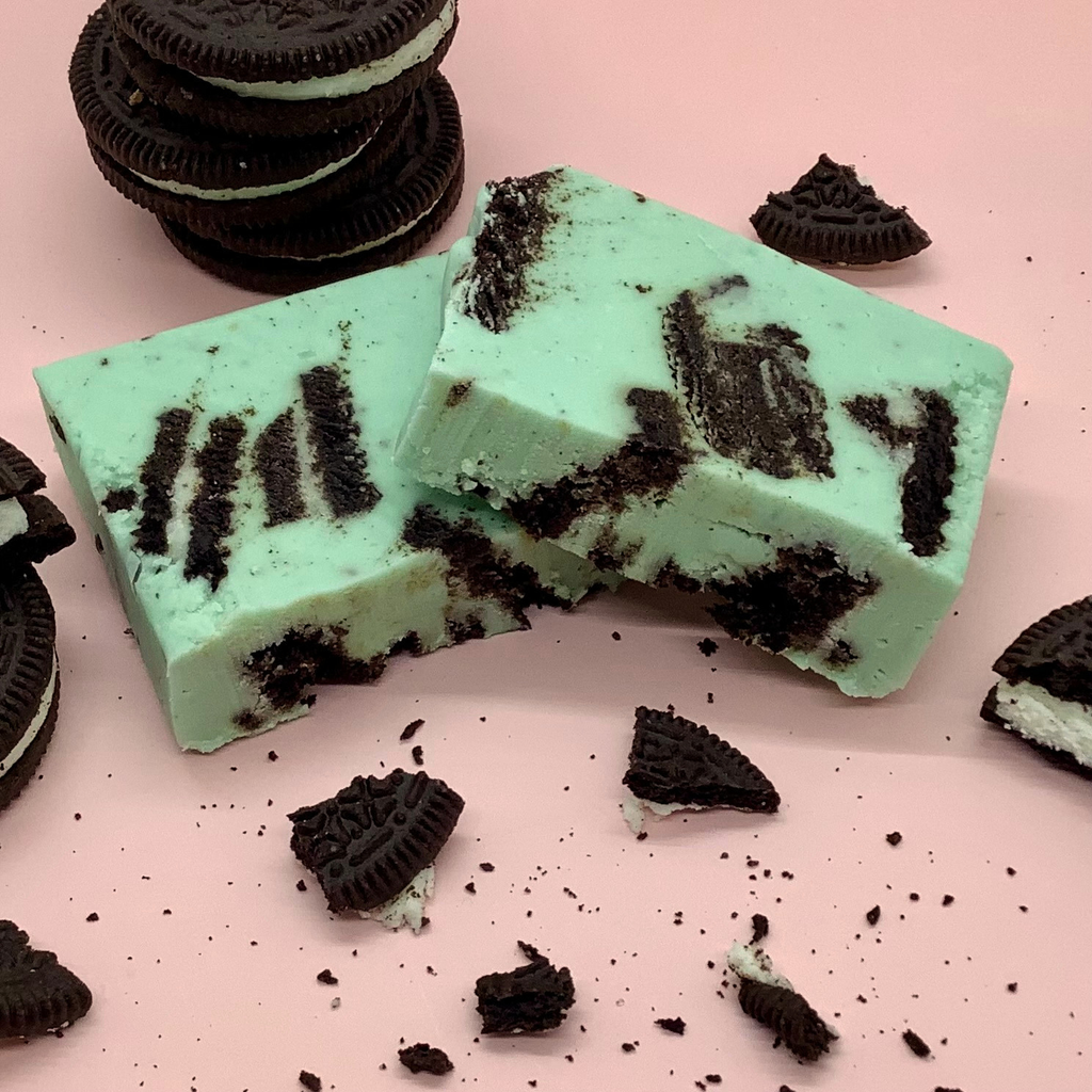 Mint Cookie Fudge bars with crushed cookies on a pink background