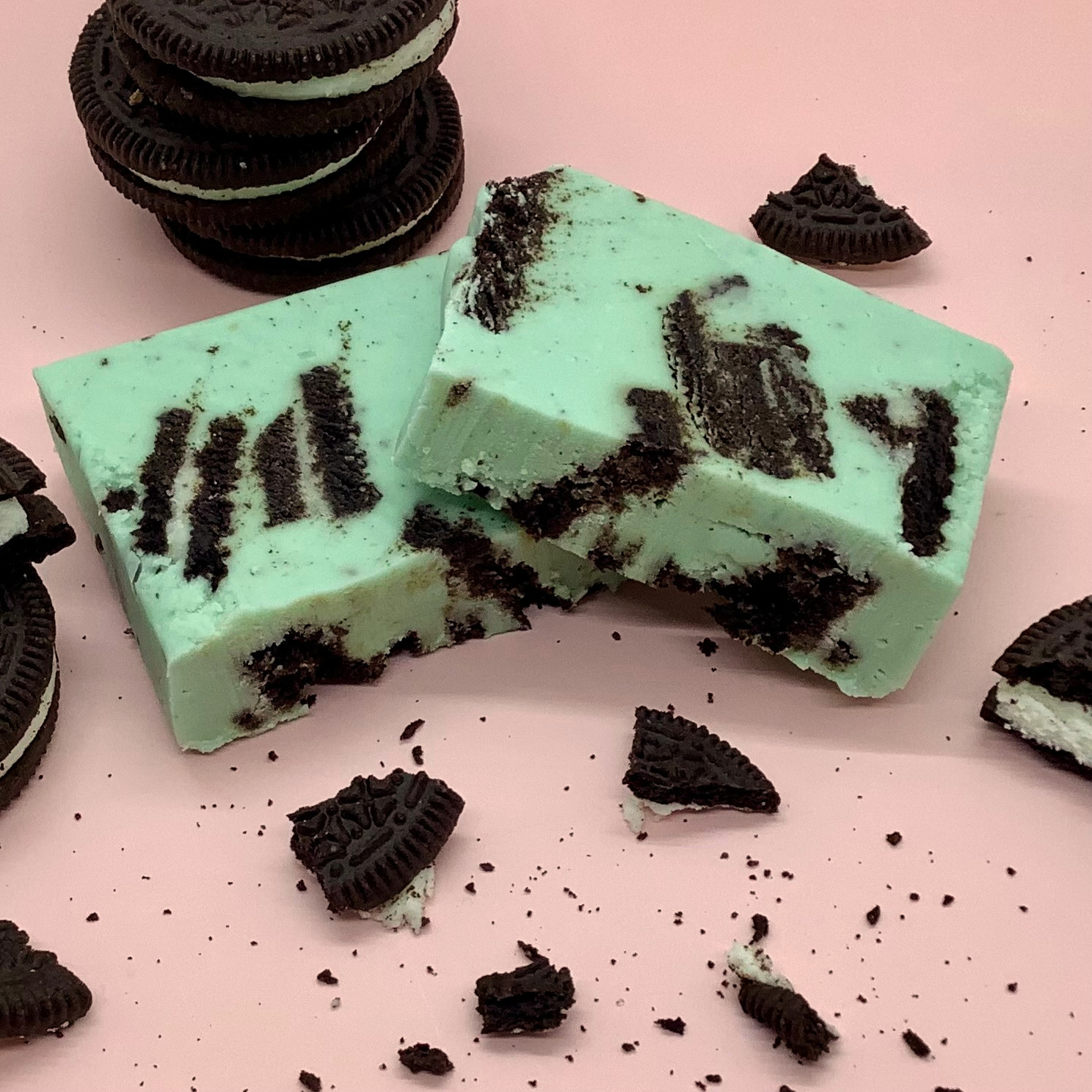 Mint Cookie Fudge bars with crushed cookies on a pink background