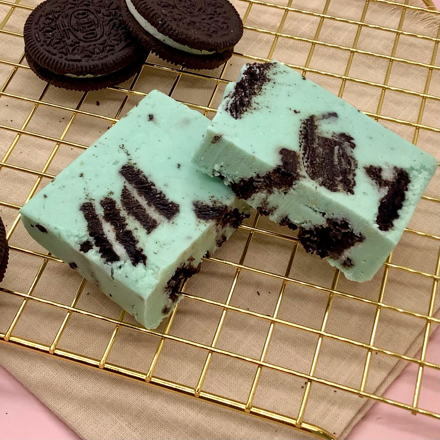 Mint Cookie Fudge squares with Oreo cookie pieces on a gold cooling rack