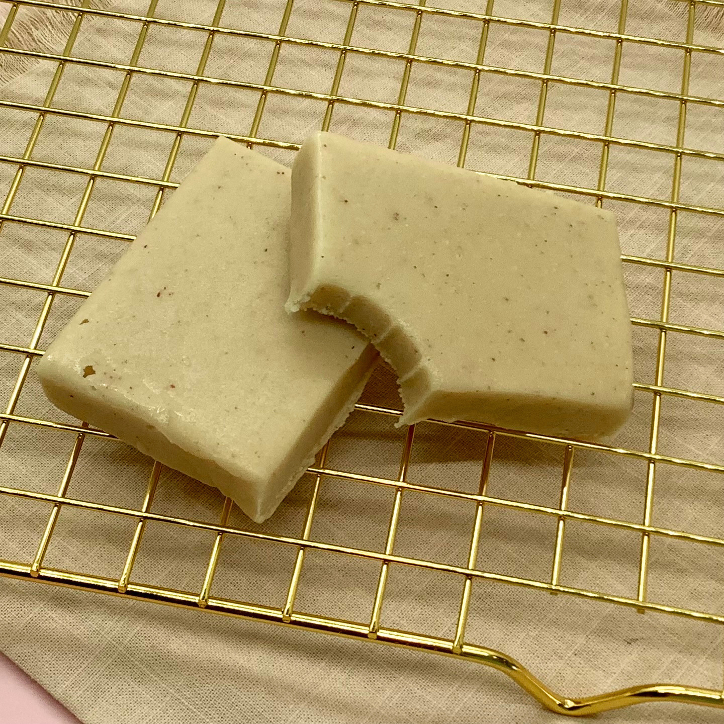 Peanut butter fudge squares on a gold cooling rack with a bite taken from one