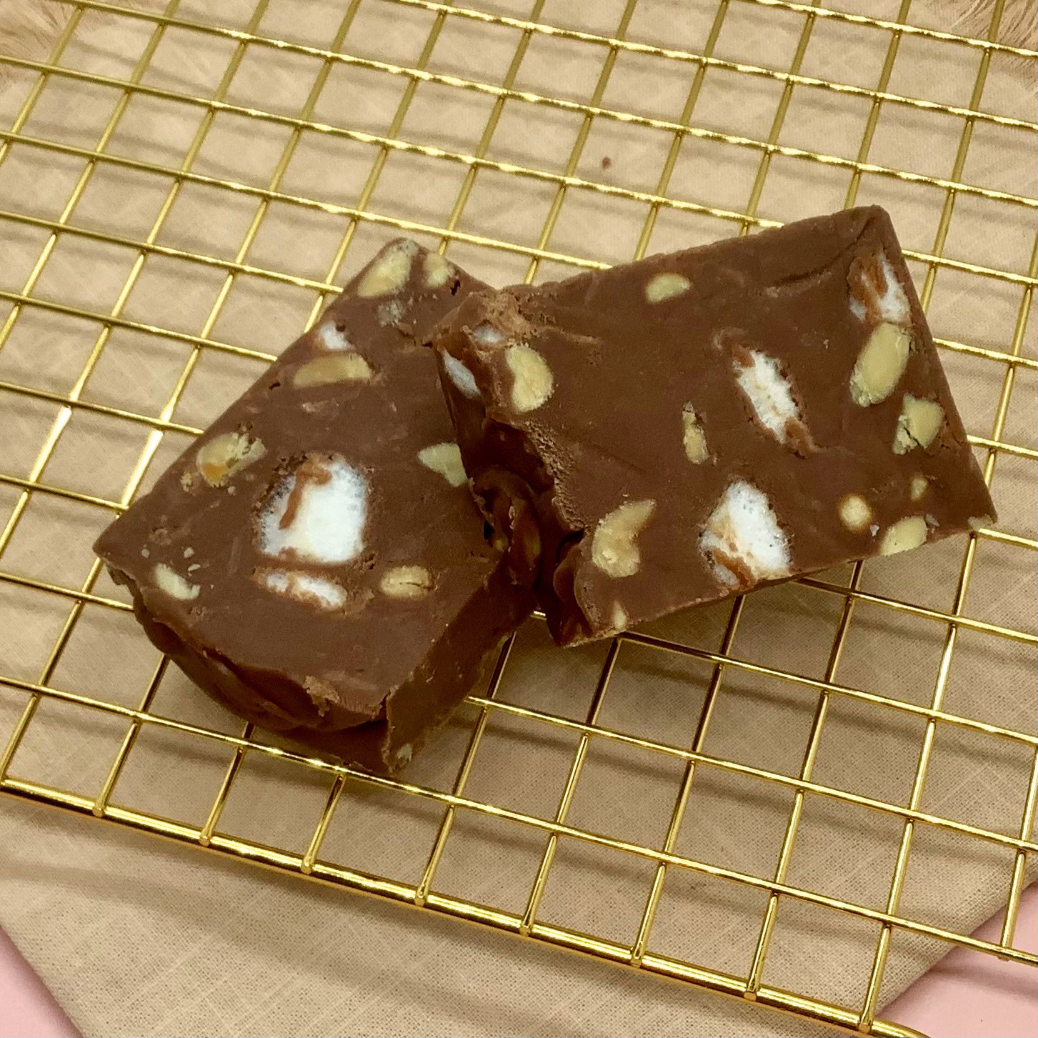 Rocky Road Fudge with marshmallows and nuts in a chocolate slab on a gold cooling rack