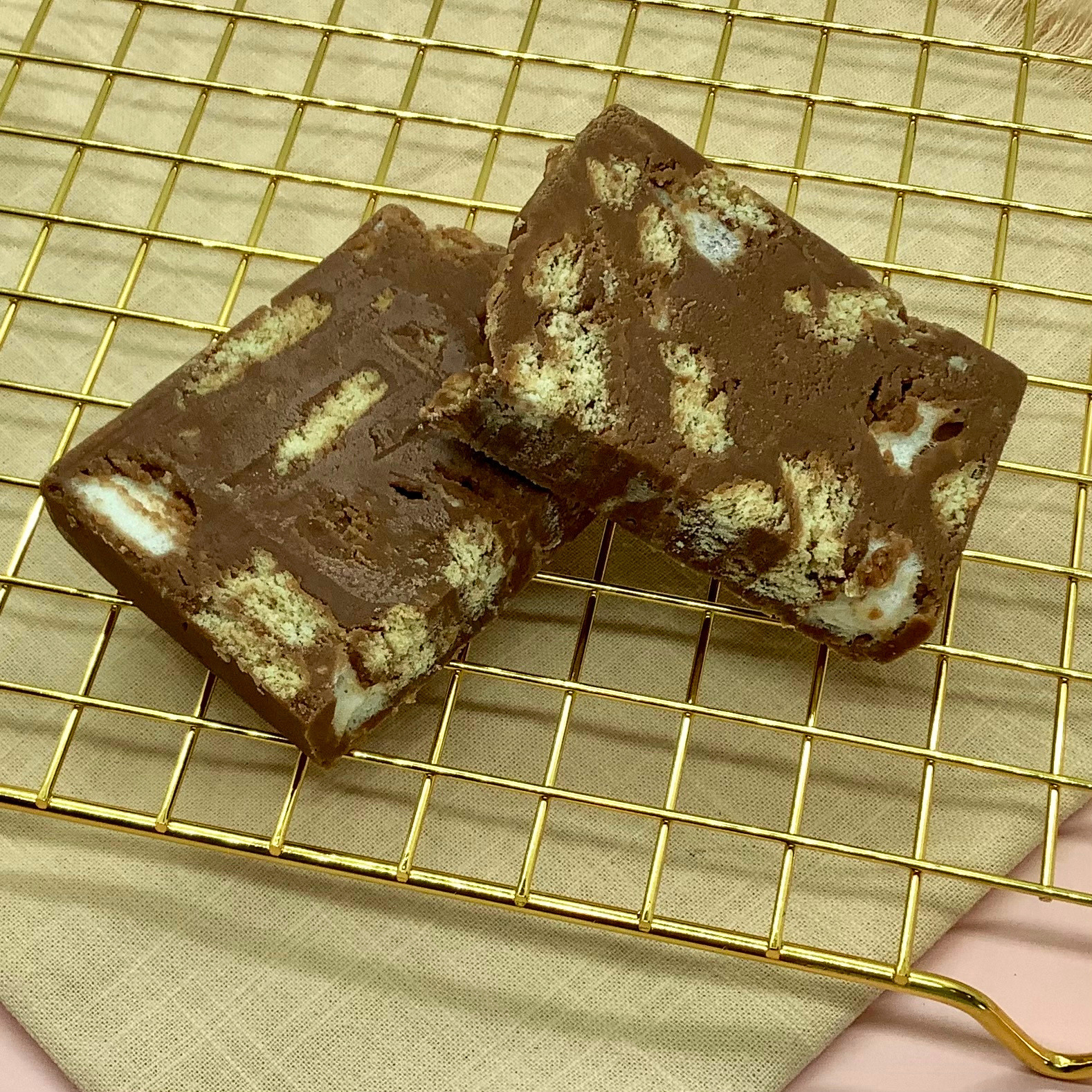 S'mores fudge with marshmallows and graham cracker bits in chocolate on a gold cooling rack.