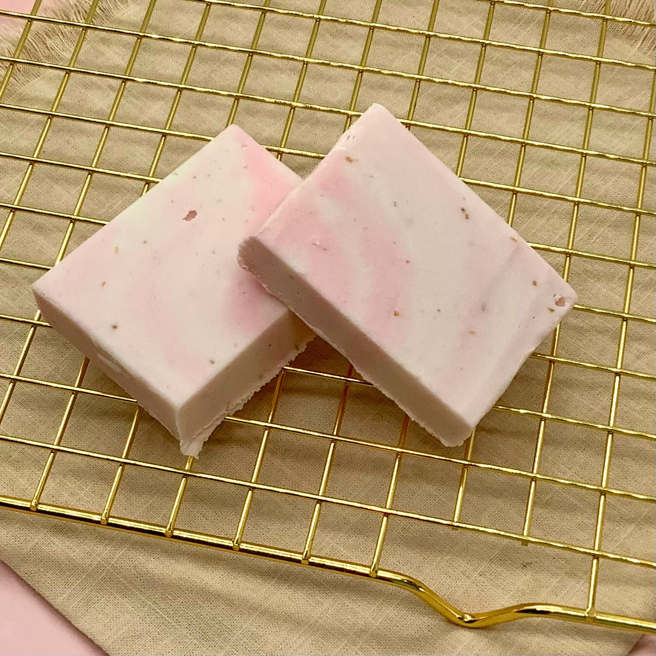 Strawberries n Cream fudge squares with pink and white marbling on a gold wire cooling rack